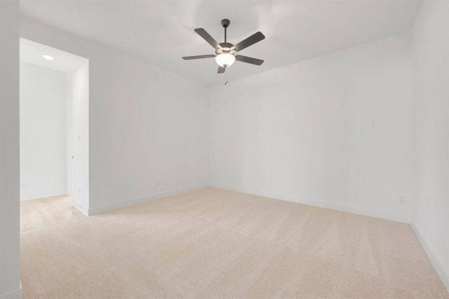 Spacious room featuring neutral carpeting, white walls, and a ceiling fan with integrated lighting Spacious room featuring neutral carpeting, white walls, and a ceiling fan with integrated lighting