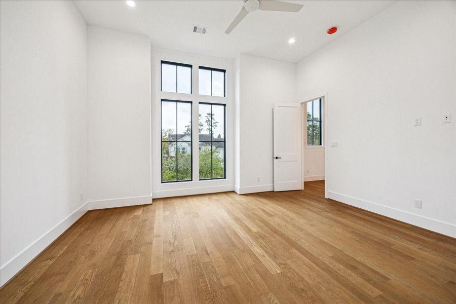 Sunlight pours through the vertical window set, creating an airy retreat ideal for a secondary suite or guest room. Oak flooring and smooth walls enhance the serene feel. *Previous Project*