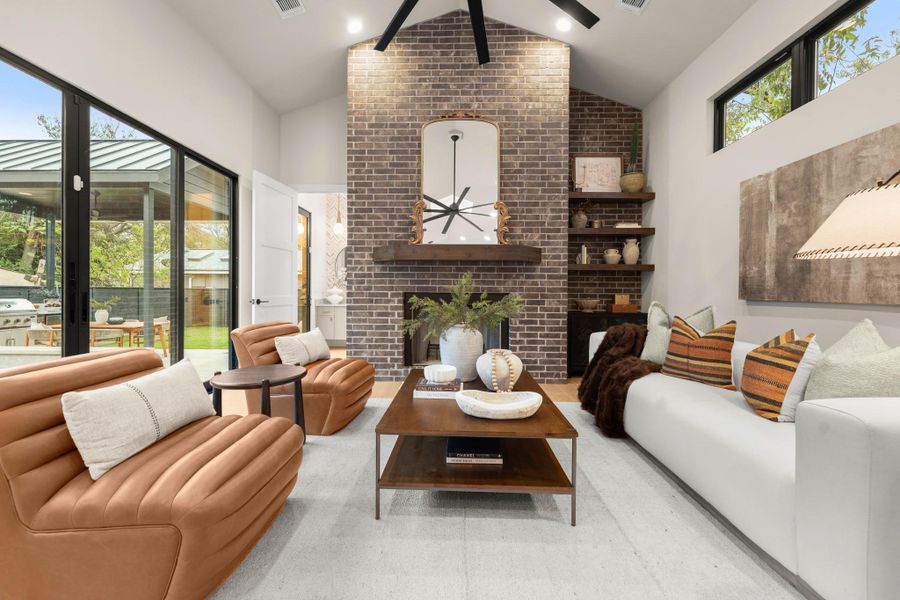 Living room with a fireplace, a ceiling fan, and high vaulted ceiling