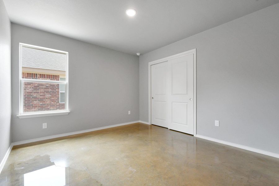 A well-lit room featuring durable concrete flooring and convenient closet storage. A well-lit room featuring durable concrete flooring and convenient closet storage.