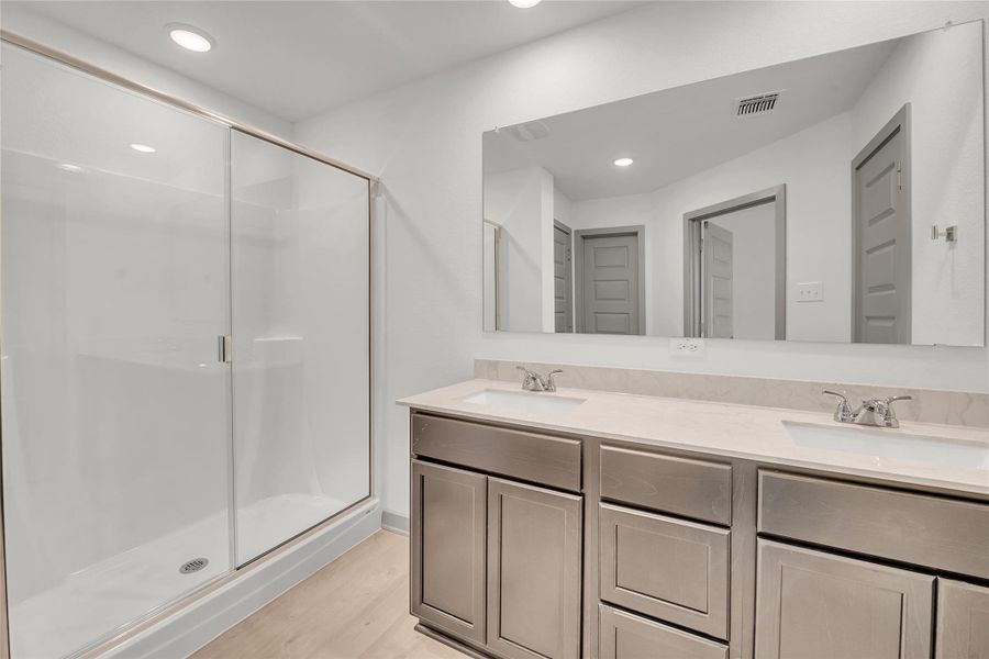 Bathroom featuring a shower stall, double vanity, light wood finished floors, and recessed lighting