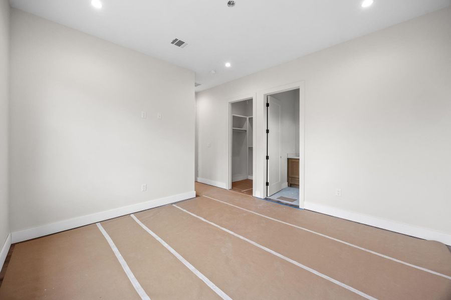 Spacious room featuring neutral painted walls, recessed lighting, white baseboards, and two doorways leading to additional areas