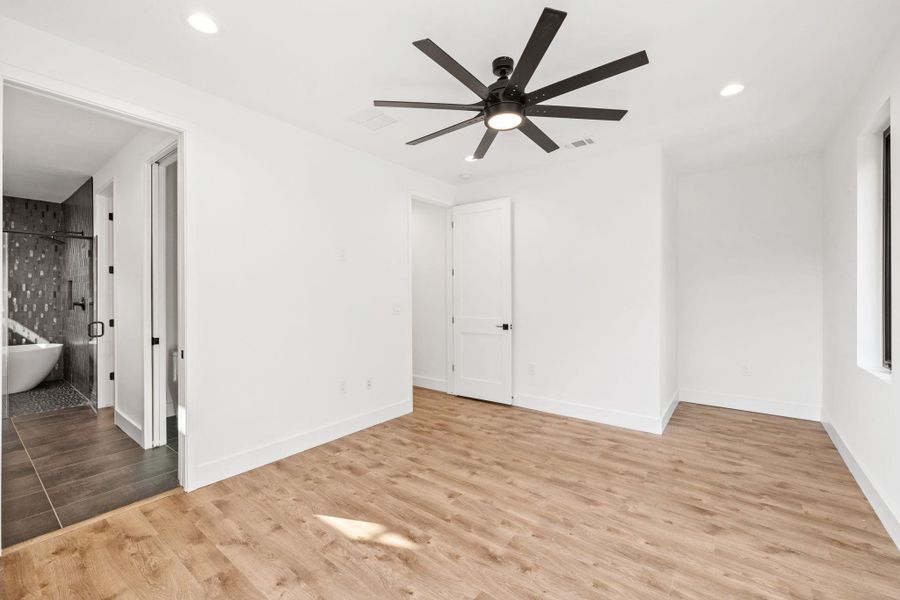 Primary bedroom with en-suite primary bath, large ceiling fan