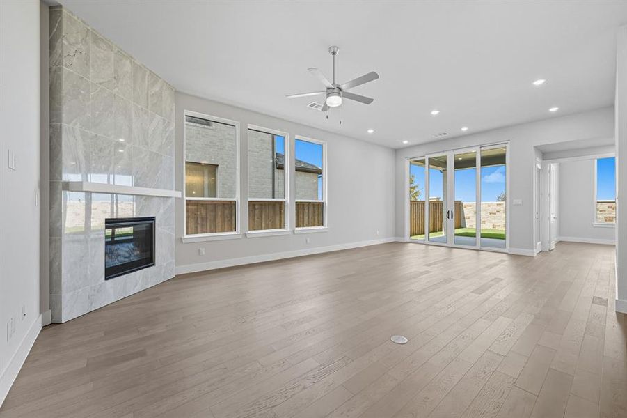 Unfurnished living room with a premium fireplace, healthy amount of natural light, light wood-style flooring, and recessed lighting Unfurnished living room with a premium fireplace, healthy amount of natural light, light wood-style flooring, and recessed lighting