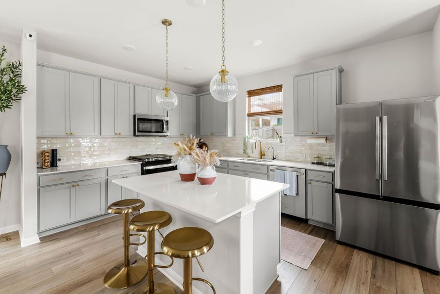 Kitchen with stainless steel appliances, gray cabinets, a kitchen bar, a kitchen island, and light wood-style flooring
