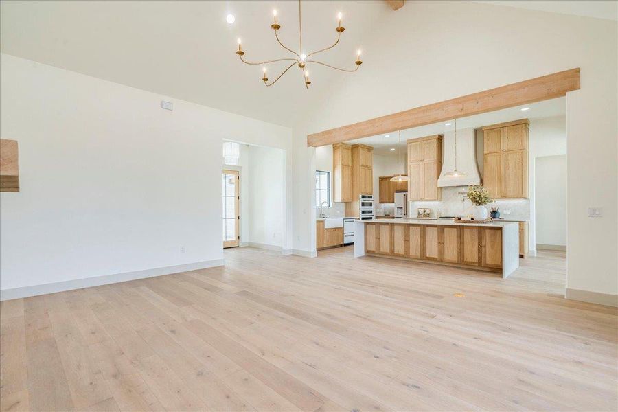 An open floorplan seamlessly connects the living area to a modern kitchen, bathed in light from soaring vaulted ceilings.