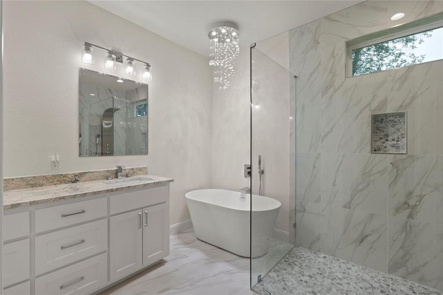 Contemporary bathroom featuring a freestanding tub, glass-enclosed shower with pebble-finish flooring, and a vanity with a stone countertop Contemporary bathroom featuring a freestanding tub, glass-enclosed shower with pebble-finish flooring, and a vanity with a stone countertop