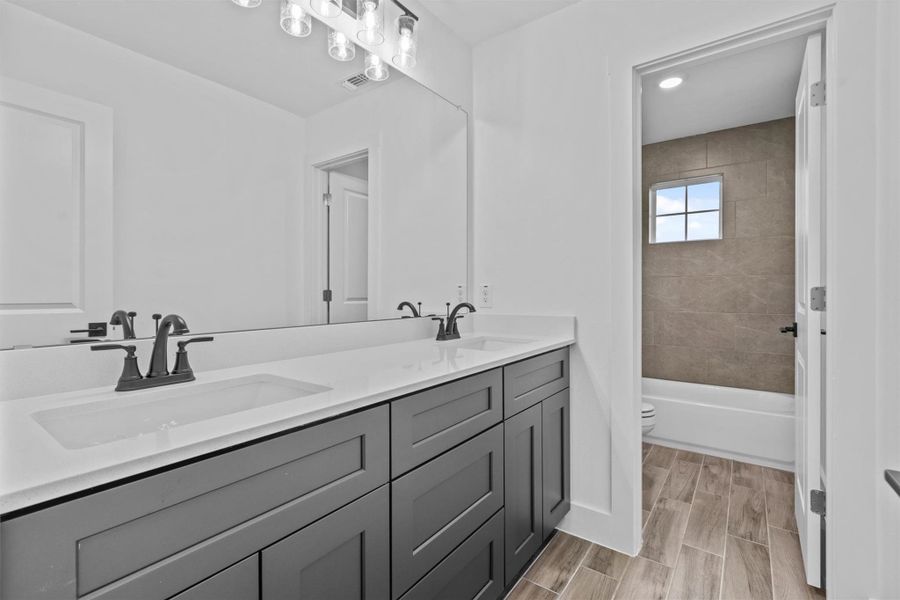 Full bathroom with toilet, vanity, and tiled shower / bath combo