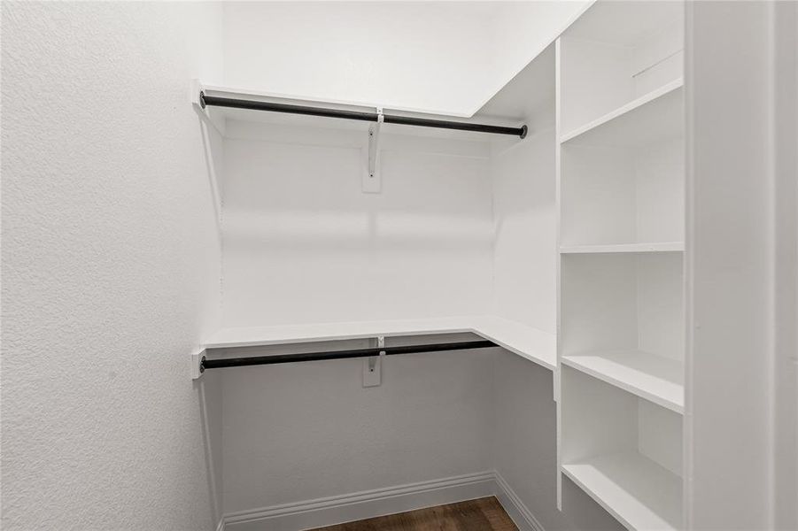 Walk in closet with dark hardwood / wood-style flooring