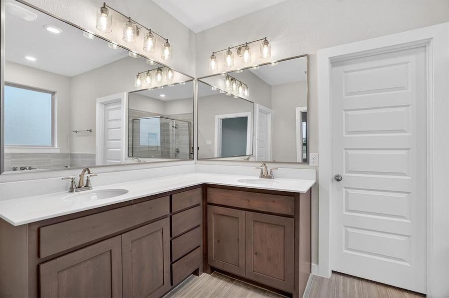 Bathroom featuring a double vanity with wood cabinetry, white countertops, and undermount sinks