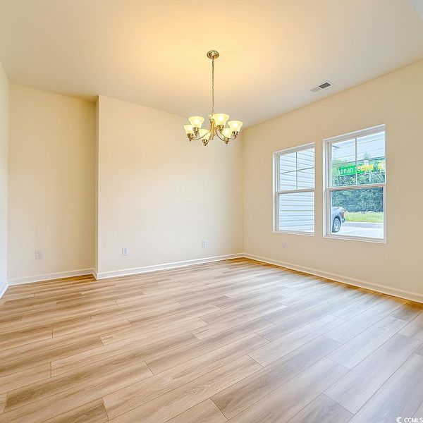 Spare room featuring a chandelier and light wood-style floors