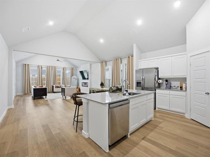 Kitchen featuring backsplash, open floor plan, white cabinetry, light wood finished floors, and recessed lighting