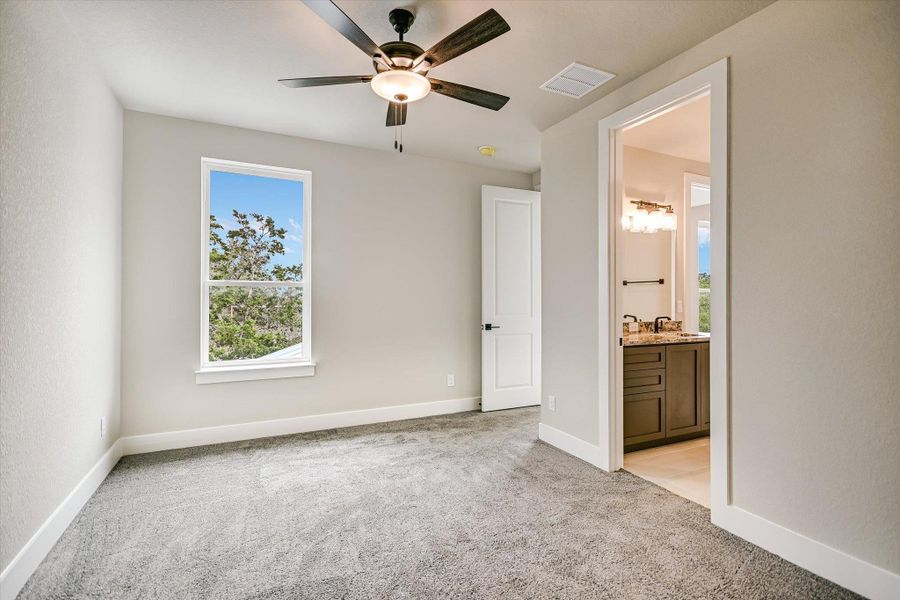 Unfurnished bedroom featuring light carpet, a ceiling fan, and ensuite bath