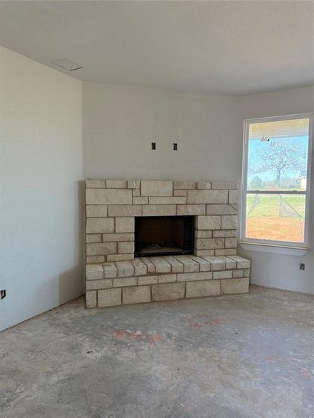 Unfurnished living room with unfinished concrete flooring and a fireplace