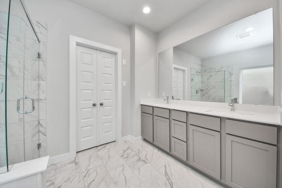 Elevate your daily routine at the elegant vanity, now equipped with double sinks, light countertops, modern hardware, and beautiful recessed lights. Sample photo of completed home with similar floor plan. Actual colors and selections may vary.