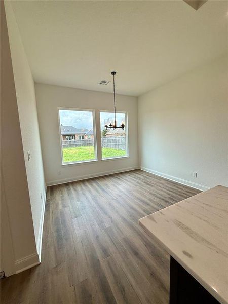 Unfurnished dining area with dark wood finished floors and hanging lights