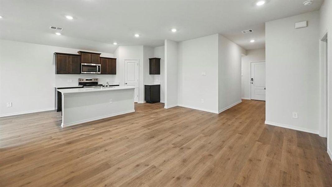 Open-concept living space featuring light wood-style flooring, recessed lighting, and a kitchen island with a white countertop