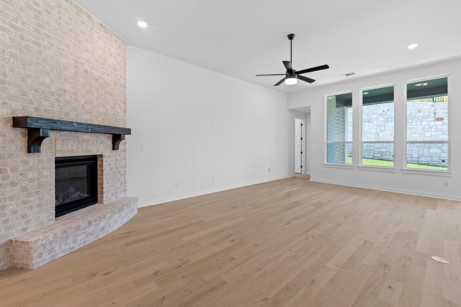 Unfurnished living room with a ceiling fan, wood finished floors, a brick fireplace, and recessed lighting