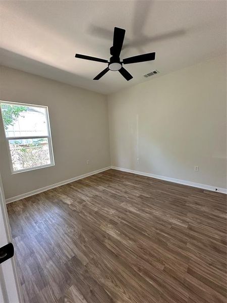 Empty room with dark wood-style floors and a ceiling fan