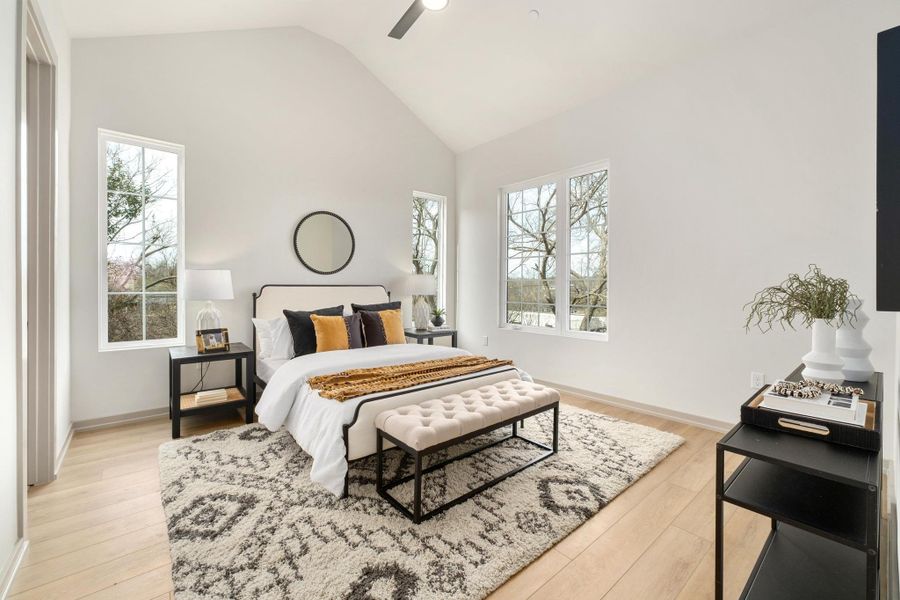 Upstairs, light hardwood flooring continues throughout, creating a cohesive and calming feel. All bedrooms feature tall vaulted ceilings, adding volume and airiness. The primary retreat feels intentionally serene, with a spacious walk-in closet and a spa-inspired bathroom featuring dual vanities and an impressive walk-in shower wrapped in floor-to-ceiling tile. Two additional bedrooms share a well-appointed bath with a dual-sink vanity, perfect for guests or flexible living.