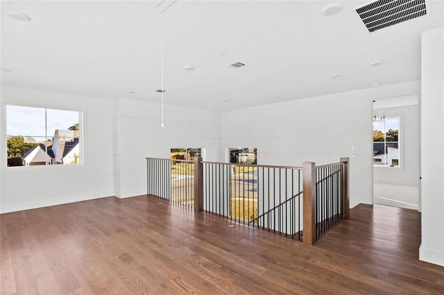 Spare room featuring plenty of natural light, wood finished floors, and attic access Spare room featuring plenty of natural light, wood finished floors, and attic access