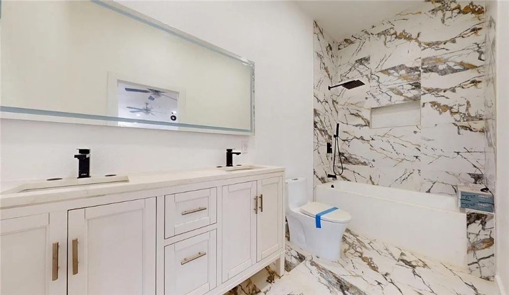 Bathroom featuring a dual vanity with white cabinetry, light-toned countertops, and matte black fixtures