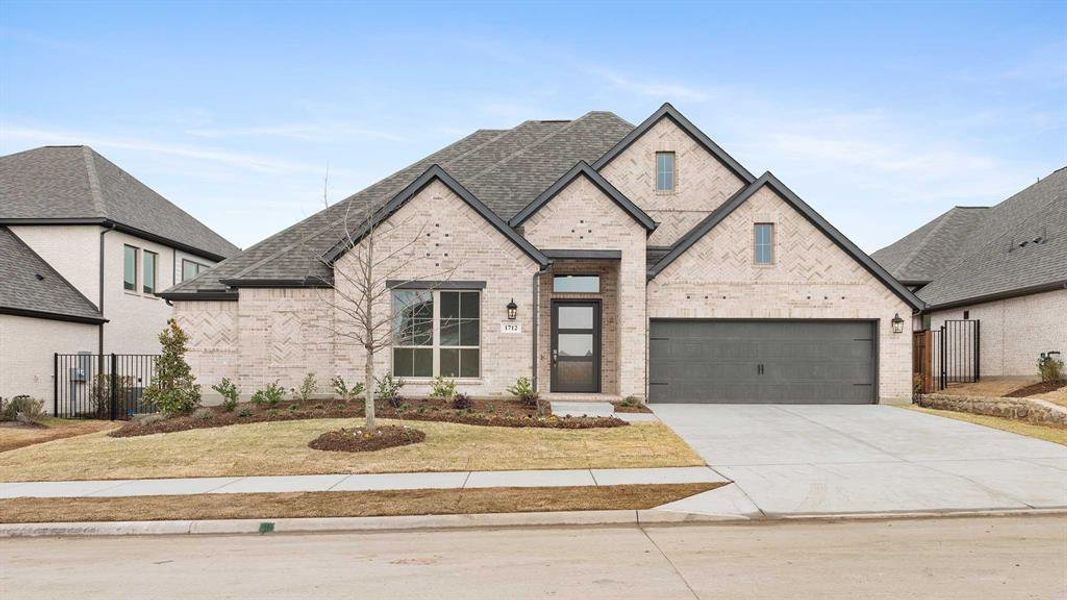 View of front of property featuring a garage and a front lawn