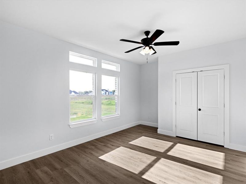 Unfurnished bedroom with dark wood-style flooring, a closet, and a ceiling fan