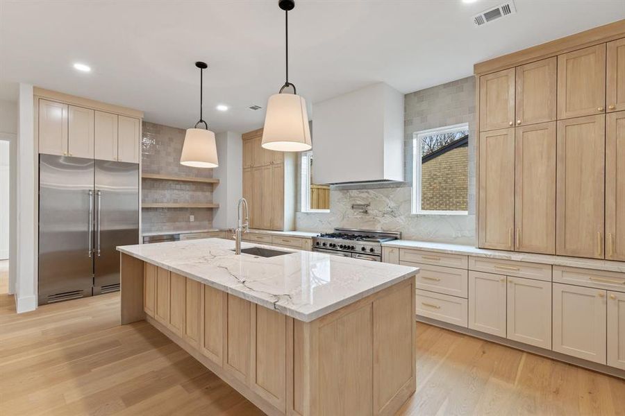 The kitchen is a true chef’s dream, featuring stunning quartzite countertops, a custom plaster vent hood, white oak custom cabinets, and Bertazzoni 48-inch range and refrigerator columns, offering both beauty and practicality.