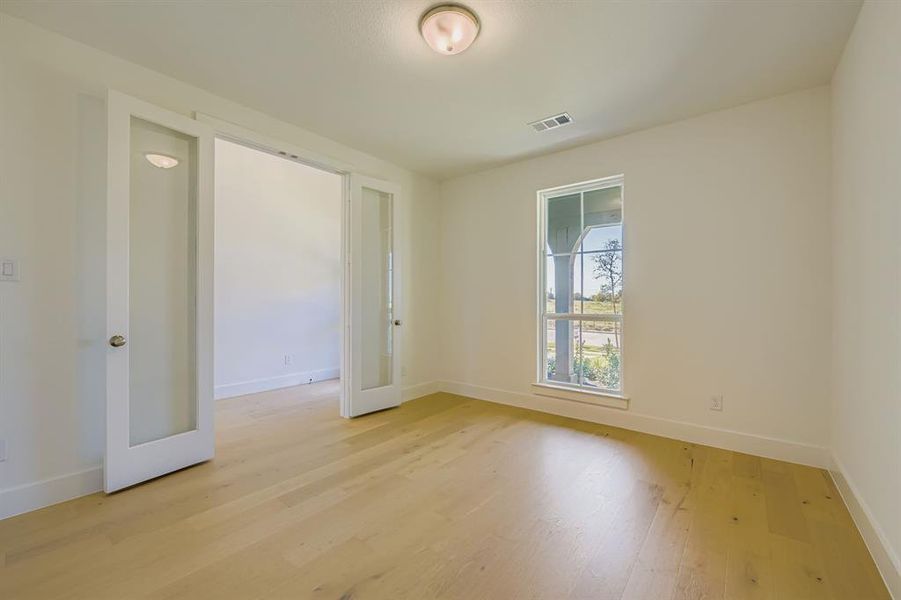 Unfurnished room featuring light wood-style flooring and french doors