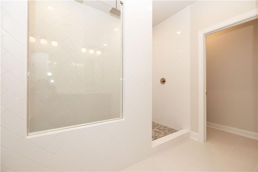 Check out this massive walk in shower!! Shower features: added Rainshower head and handheld in Champagne Bronze with upgraded  4x6 Iced Polished tile with Artic White grout laid with Herringbone pattern to ceiling,Venetian Pebble Mosaic tile flooring in