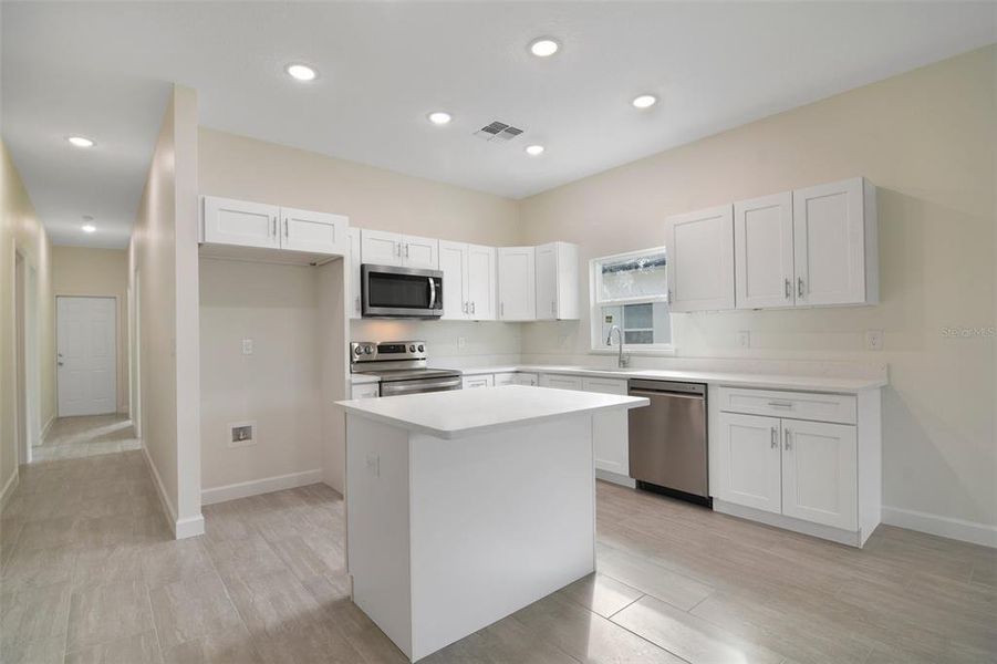 The neutral color palette perfectly compliments a spacious kitchen at the heart of it all featuring desirable shaker style cabinetry, ISLAND with breakfast bar seating, solid surface counters and large pantry for ample storage.