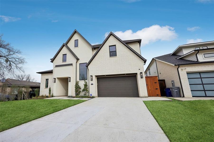 View of front facade with a gate, driveway, an attached garage, and brick siding