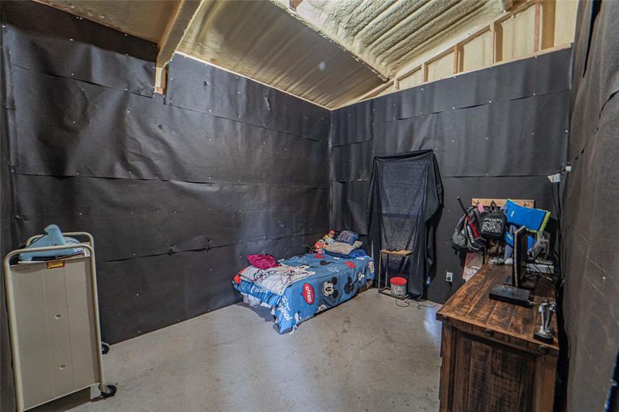 Bedroom with concrete flooring and vaulted ceiling