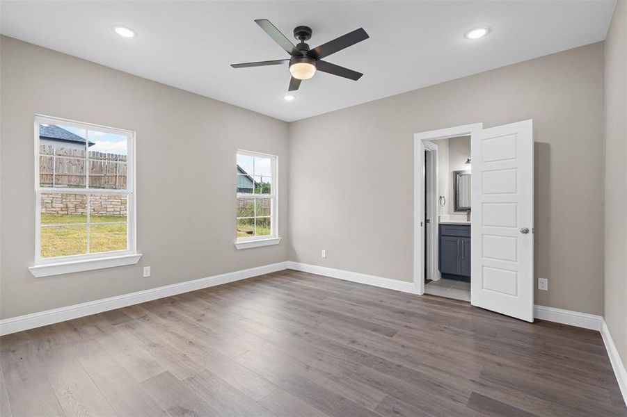 Unfurnished bedroom with dark wood finished floors, ceiling fan, recessed lighting, and ensuite bath Unfurnished bedroom with dark wood finished floors, ceiling fan, recessed lighting, and ensuite bath