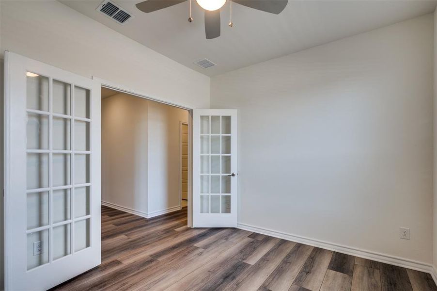 Empty room featuring french doors, ceiling fan, and dark wood-type flooring Empty room featuring french doors, ceiling fan, and dark wood-type flooring