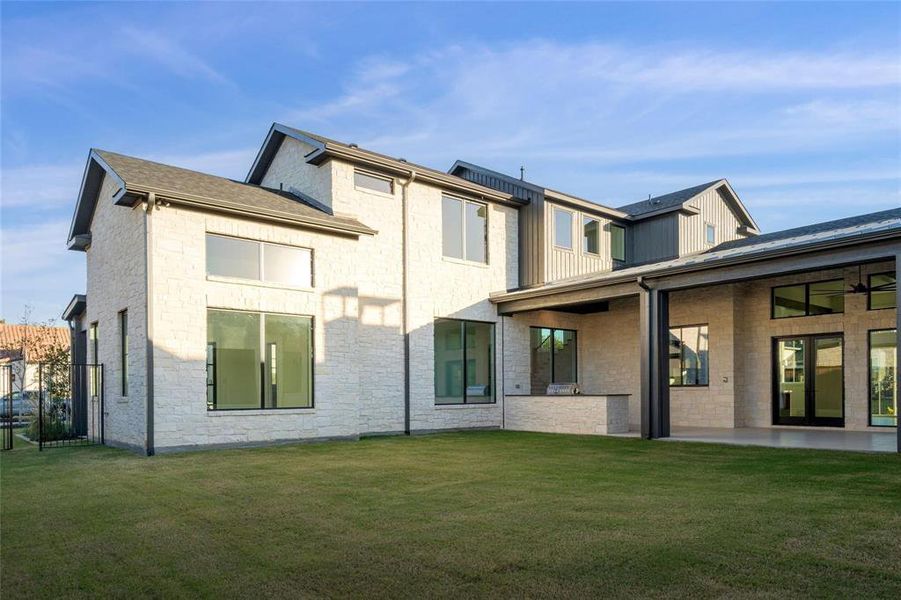 Rear view of property with a lawn, a patio area, and stone siding Rear view of property with a lawn, a patio area, and stone siding