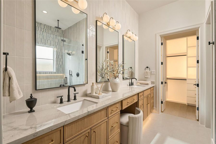 A closer look at the primary vanity showcases Mount Blanc Quartzite countertops, abundant storage, and a dedicated makeup station, with direct access to one of the suite’s two custom closets.