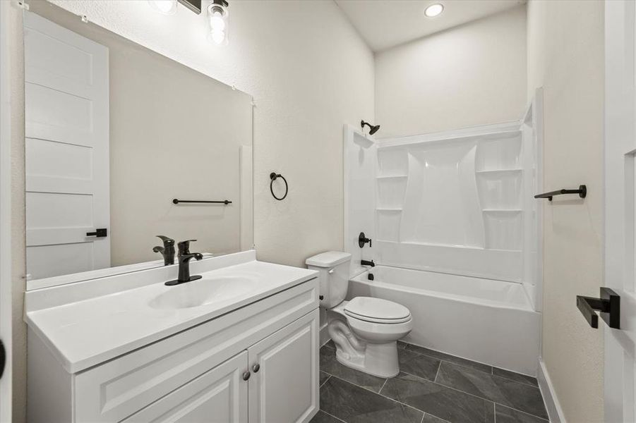 Bathroom featuring shower combination, vanity, dark tile patterned flooring, and recessed lighting Bathroom featuring shower combination, vanity, dark tile patterned flooring, and recessed lighting