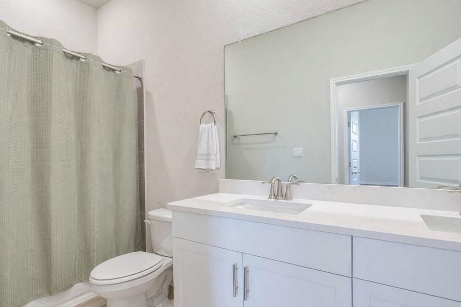 A well-lit guest bathroom features a spacious double vanity and pristine white cabinetry.