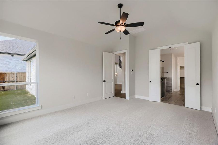 Carpeted room with a large window overlooking a fenced yard