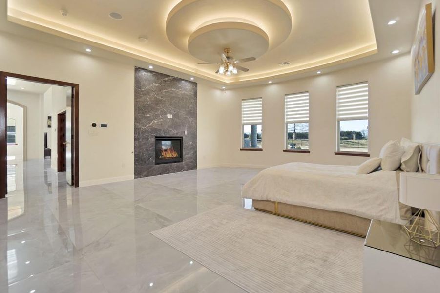 Bedroom featuring a premium fireplace and a tray ceiling