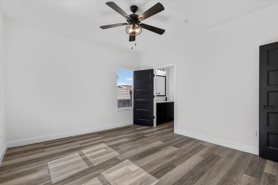 Rich wood floors and clean white walls anchor this bedroom with an attached bath. Rich wood floors and clean white walls anchor this bedroom with an attached bath.