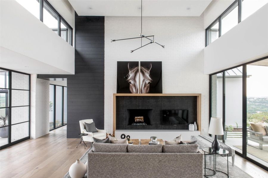 Living area with a fireplace, wood finished floors, and a high ceiling