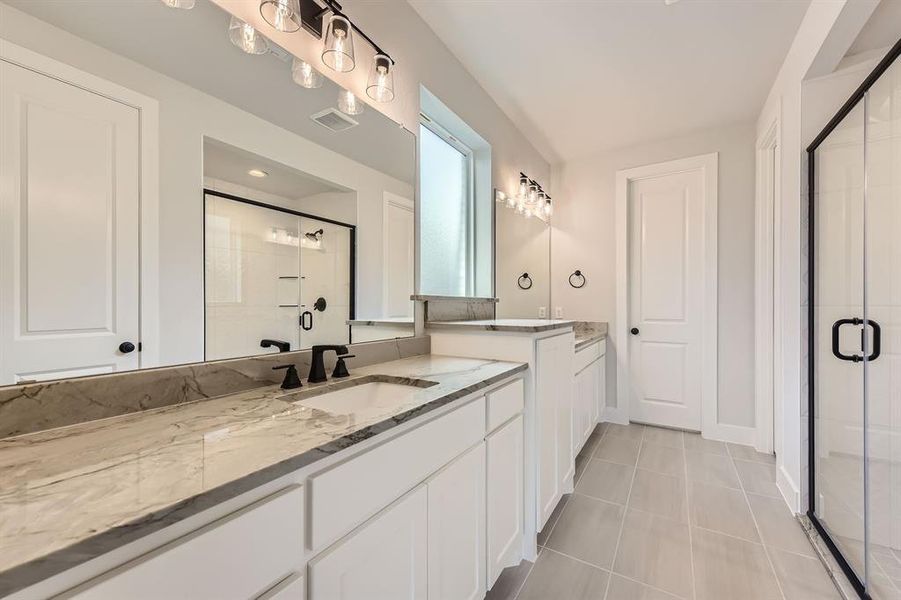 Full bathroom with a stall shower, two vanities, tile patterned floors, and baseboards