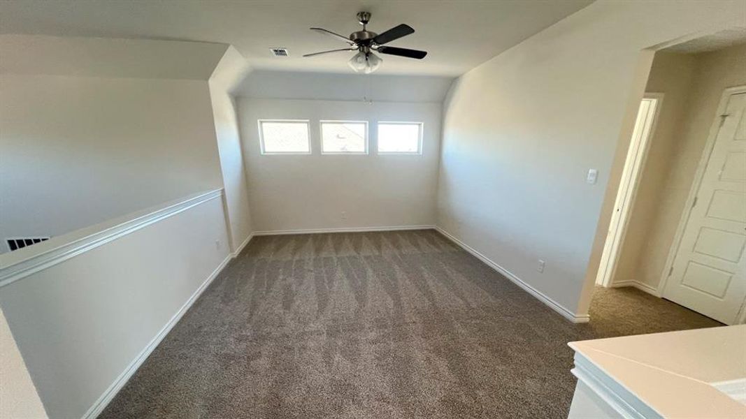 Spare room with dark colored carpet and a ceiling fan