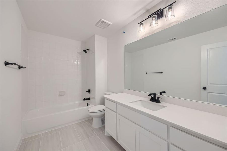 Full bathroom featuring tiled shower / bath, vanity, tile patterned flooring, and toilet