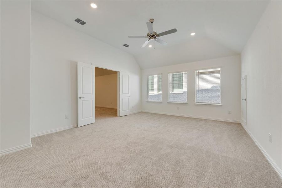 Carpeted spare room with ceiling fan and lofted ceiling