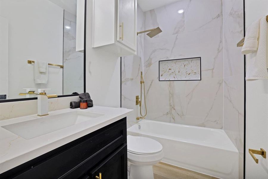 Full bathroom featuring hardwood / wood-style floors, vanity, tiled shower / bath combo, and toilet