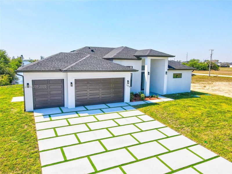 View of front of property featuring , an attached 3 car garage, custom driveway, and a front yard